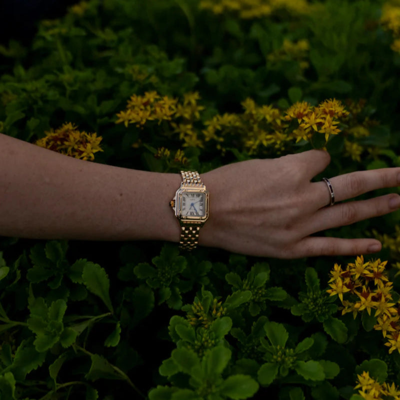 Leonie – Goldene Uhr mit quadratischem Gehäuse.